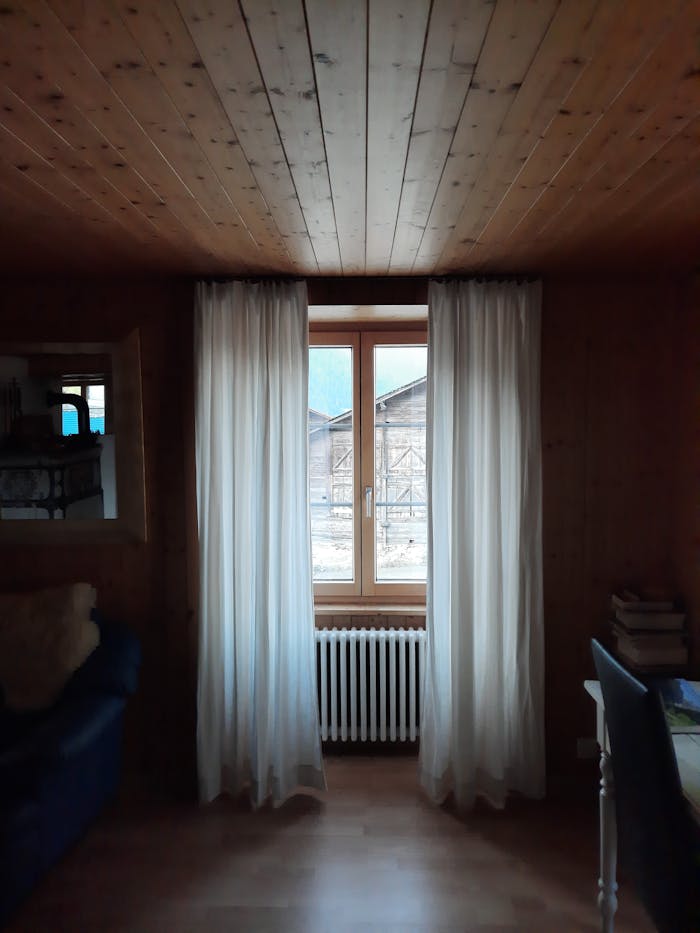 A serene interior shot featuring wooden walls and a window view of a rustic barn.