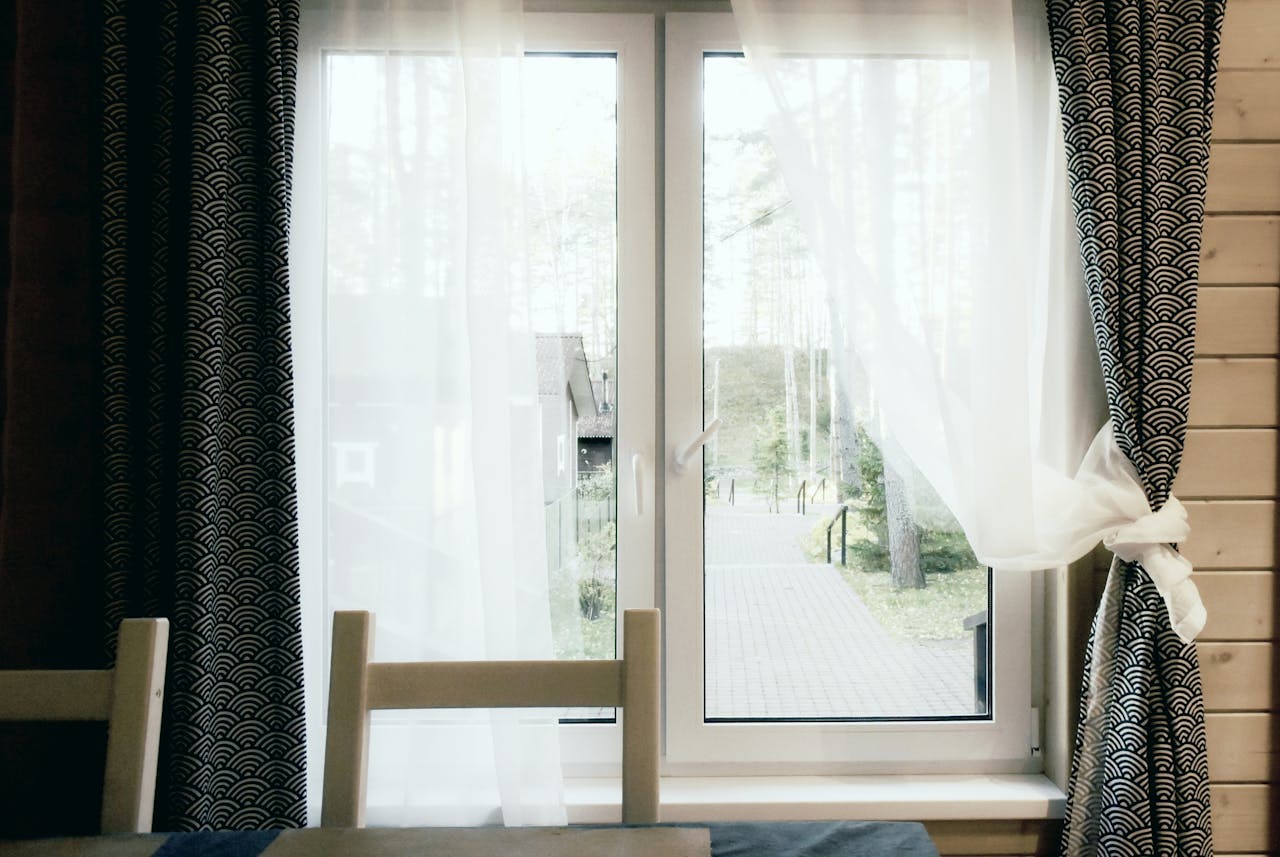 Warm interior setting featuring a window with patterned curtains framing an outdoor view.