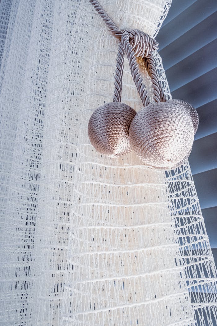 Close-up view of elegant white curtains with textured fabric and decorative tiebacks.